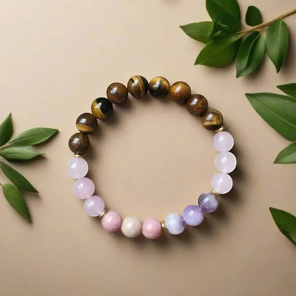 Ascendancy Gems beaded bracelet with natural Tiger Eye, Amethyst, Rose Quartz, and Rhodonite stones on a beige surface.