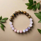 Ascendancy Gems beaded bracelet with natural Tiger Eye, Amethyst, Rose Quartz, and Rhodonite stones on a beige surface.