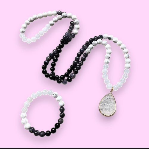 Ascendancy Gems Awakening Mala Set: 108-bead necklace & bracelet with white howlite, black onyx, and quartz, featuring a teardrop quartz pendant.