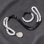 Ascendancy Gems Awakening Mala Set: 108-bead necklace & bracelet with white howlite, black onyx, and quartz beads. Features a teardrop quartz pendant.