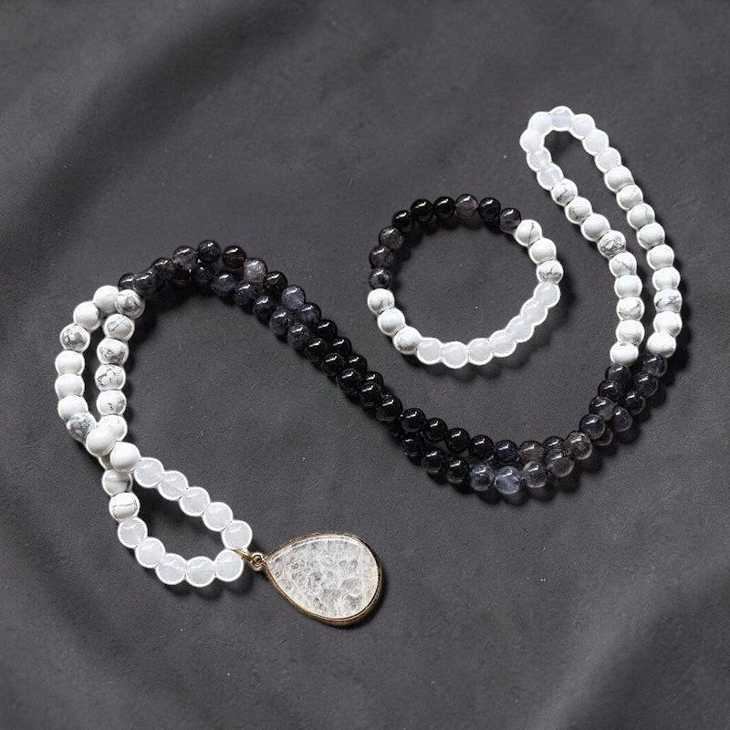 Ascendancy Gems Awakening Mala Set: 108-bead necklace & bracelet with white howlite, black onyx, and quartz beads. Features a teardrop quartz pendant.