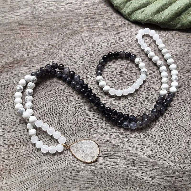 Ascendancy Gems Awakening Mala Set: 108-bead necklace & bracelet with white howlite, black onyx, and quartz beads. Features a teardrop quartz pendant.