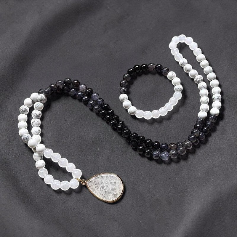 Ascendancy Gems Awakening Mala Set: 108-bead necklace & bracelet with white howlite, black onyx, and quartz beads. Features a teardrop quartz pendant.