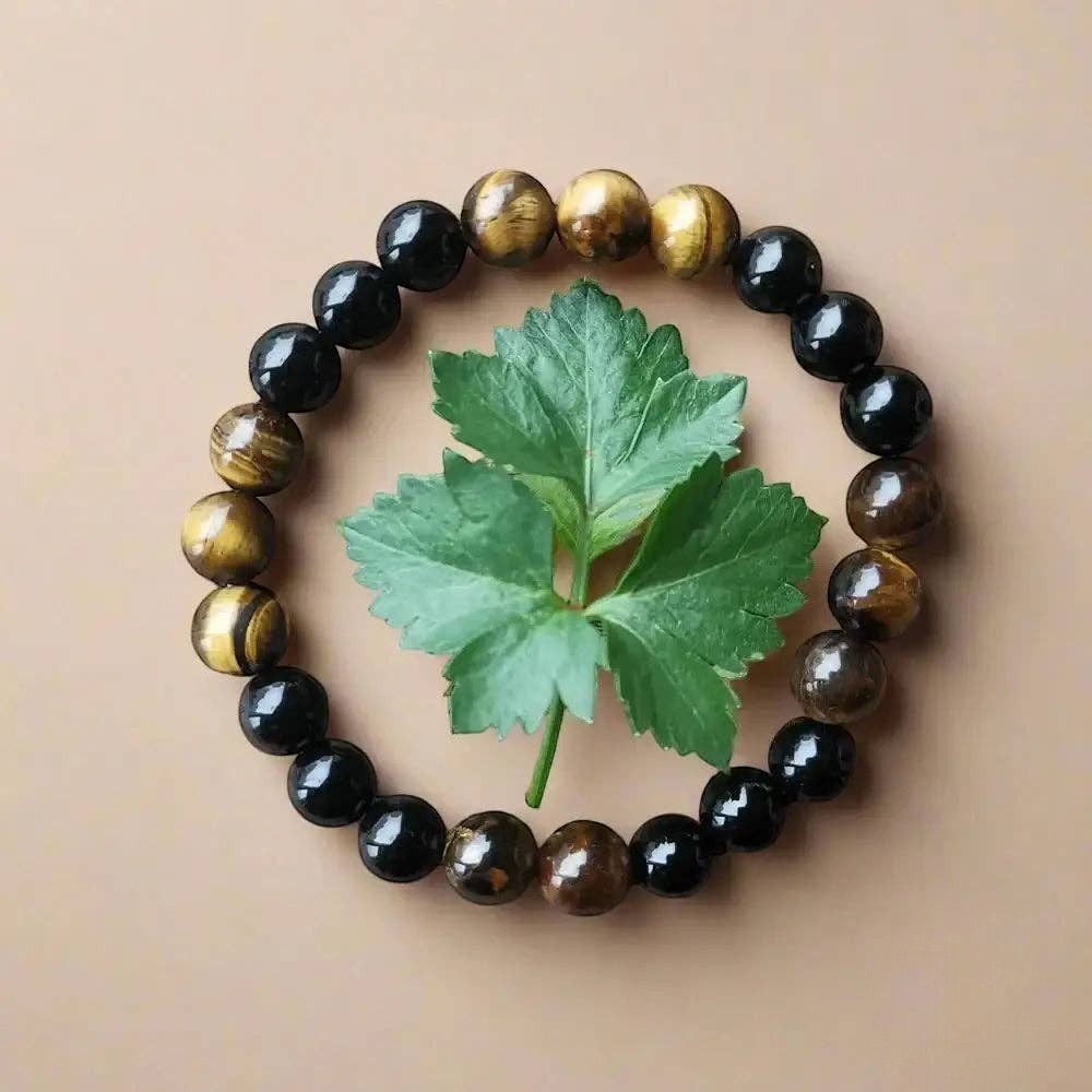 Ascendancy Gems beaded bracelet with alternating black onyx and tiger eye gemstones surrounding a green leaf.