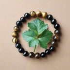 Ascendancy Gems handcrafted mala bracelet with alternating natural black onyx and tiger eye beads on beige background
