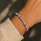 Ascendancy Gems one-of-a-kind purple smoked opal beaded bracelet with flashes of fiery color on a wrist.