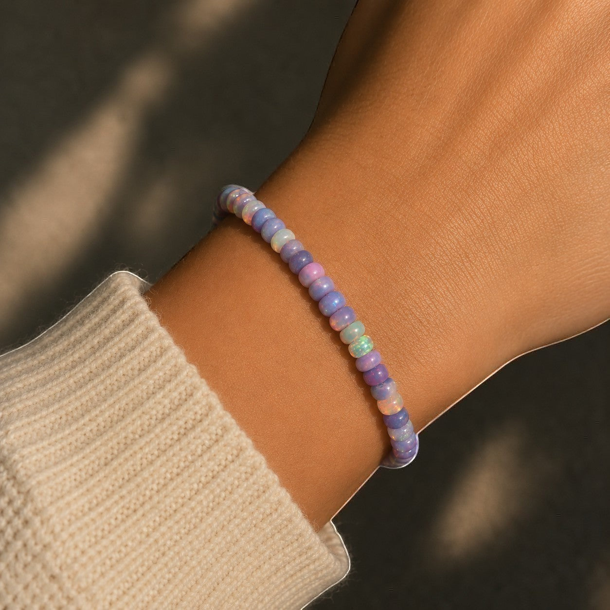 Ascendancy Gems one-of-a-kind purple smoked opal beaded bracelet with flashes of fiery color on a wrist.
