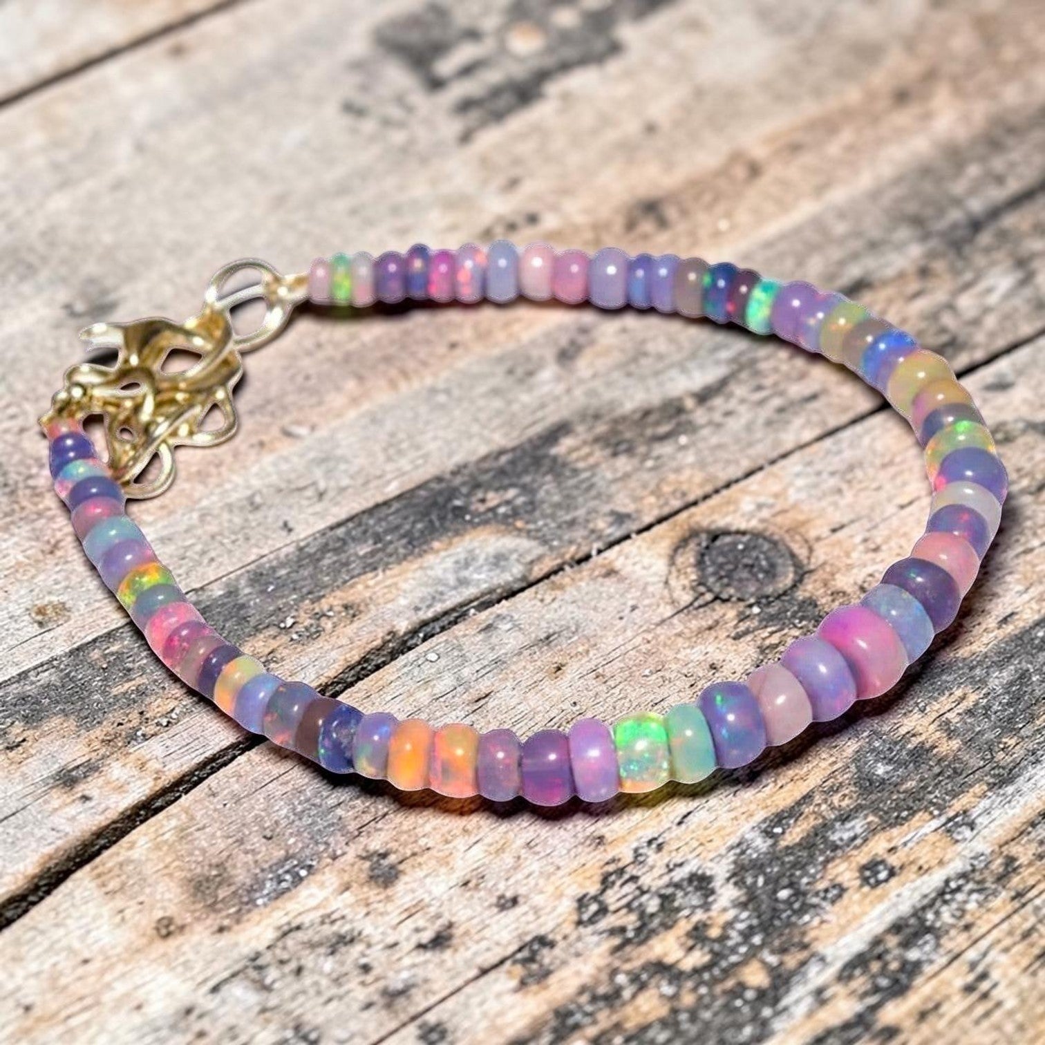 Ascendancy Gems one-of-a-kind bracelet featuring iridescent purple smoked Ethiopian fire opal beads with gold clasp.