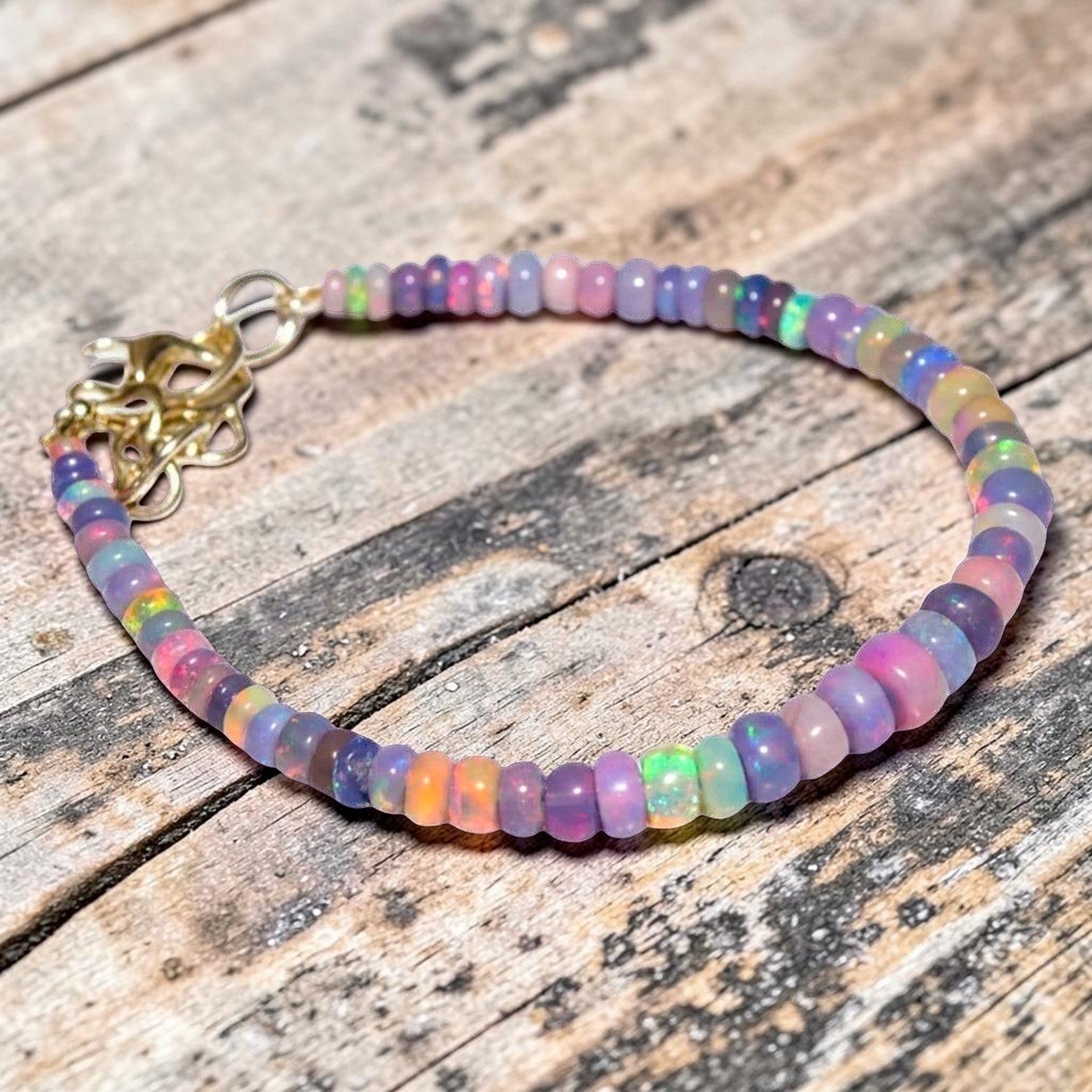 Ascendancy Gems one-of-a-kind bracelet featuring iridescent purple smoked Ethiopian fire opal beads with gold clasp.
