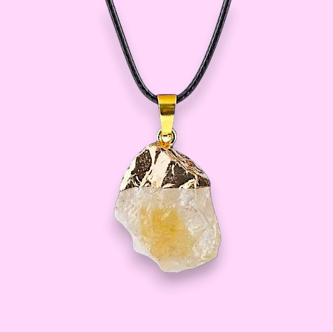 Ascendancy Gems raw crystal necklace with a pale yellow stone and gold cap on a black cord.