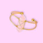 Ascendancy Gems Celestial Rose Quartz Bracelet with a raw pink quartz crystal wrapped in gold wire on a gold cuff.