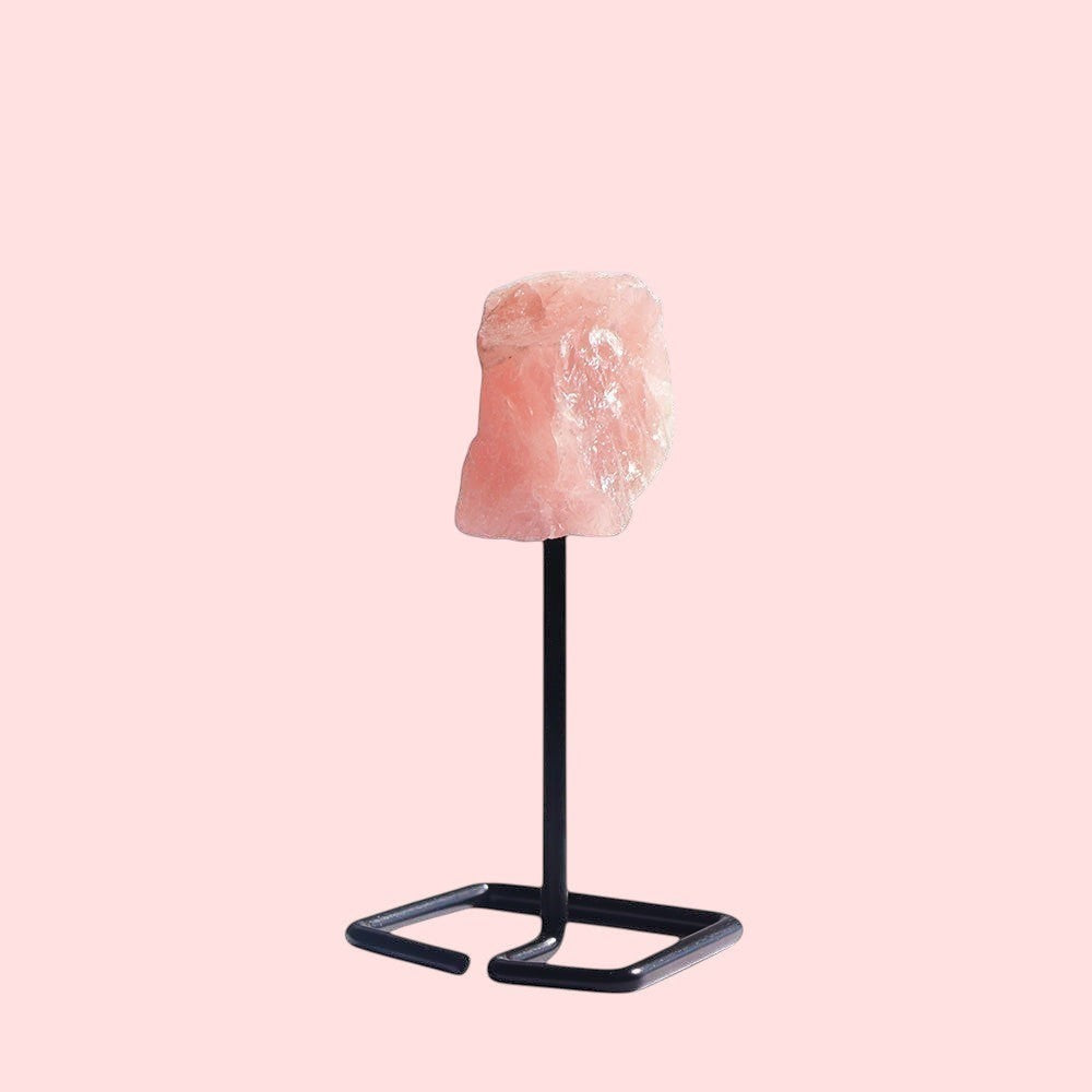 Ascendancy Gems raw rose quartz crystal on a minimalist black metal stand, approx. 4 inches tall.
